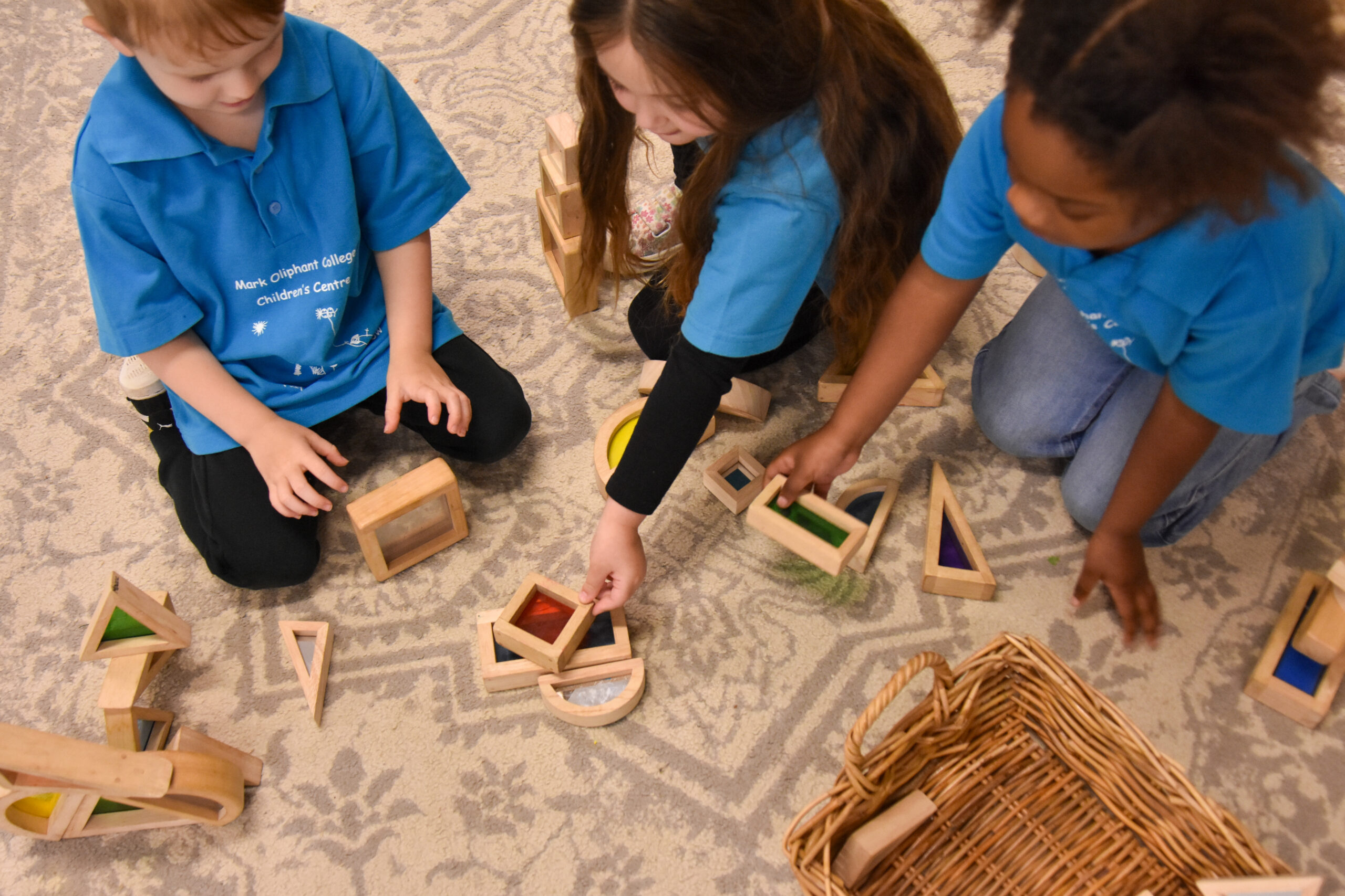 Children's Centre students building with wooden blocks on a patterned rug