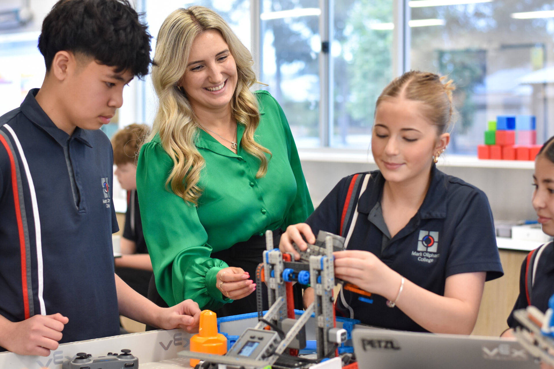 Secondary students assembling a robotics project with their teacher