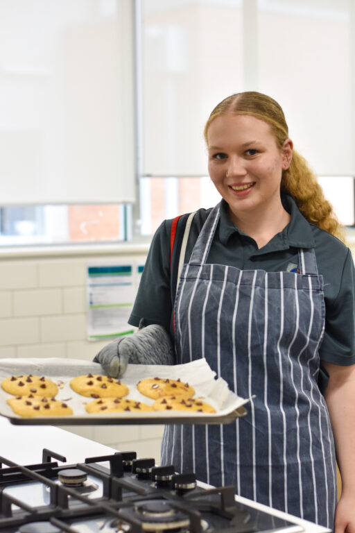 Student holding a tray of freshly baked cookies in the food technology kitchen