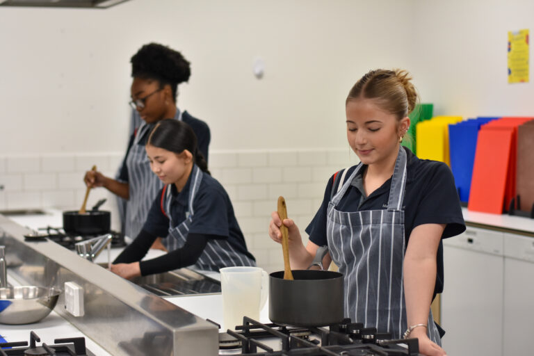 Students cooking at the stove in the food technology kitchen