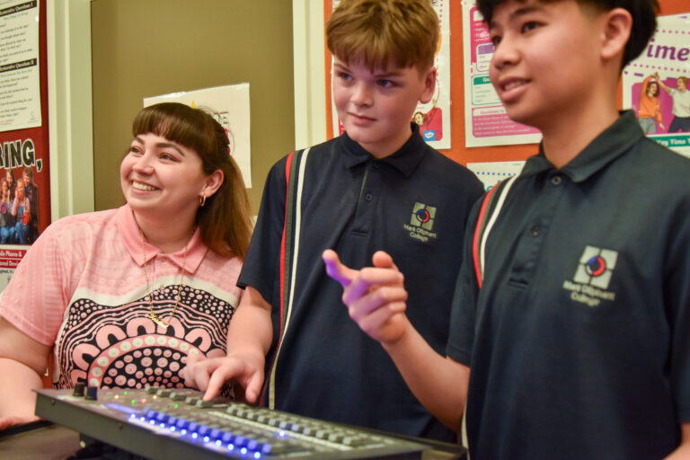 Teacher and two students working at a music production mixing desk
