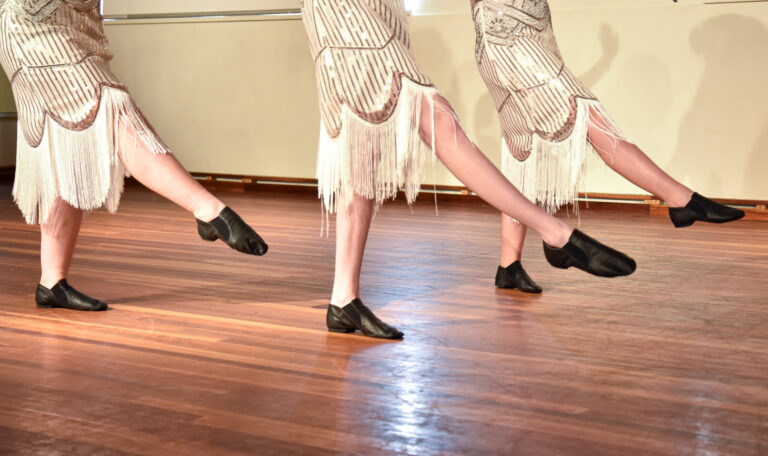 Close-up of students' feet in fringed costumes during a dance rehearsal