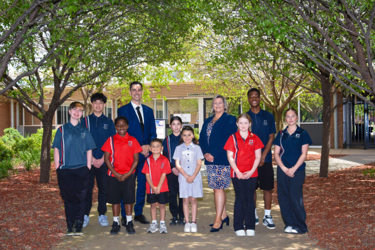 Students from across year levels standing with staff in the school grounds
