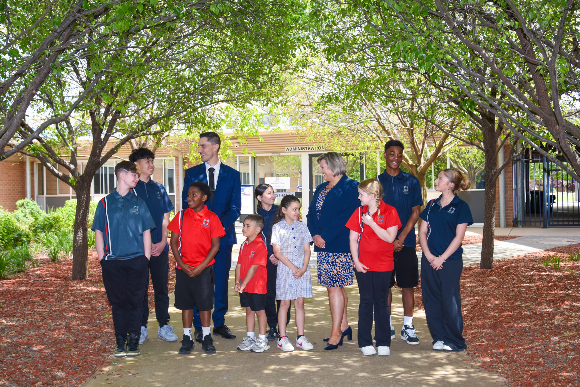 Students from across year levels standing with a staff member in the school grounds