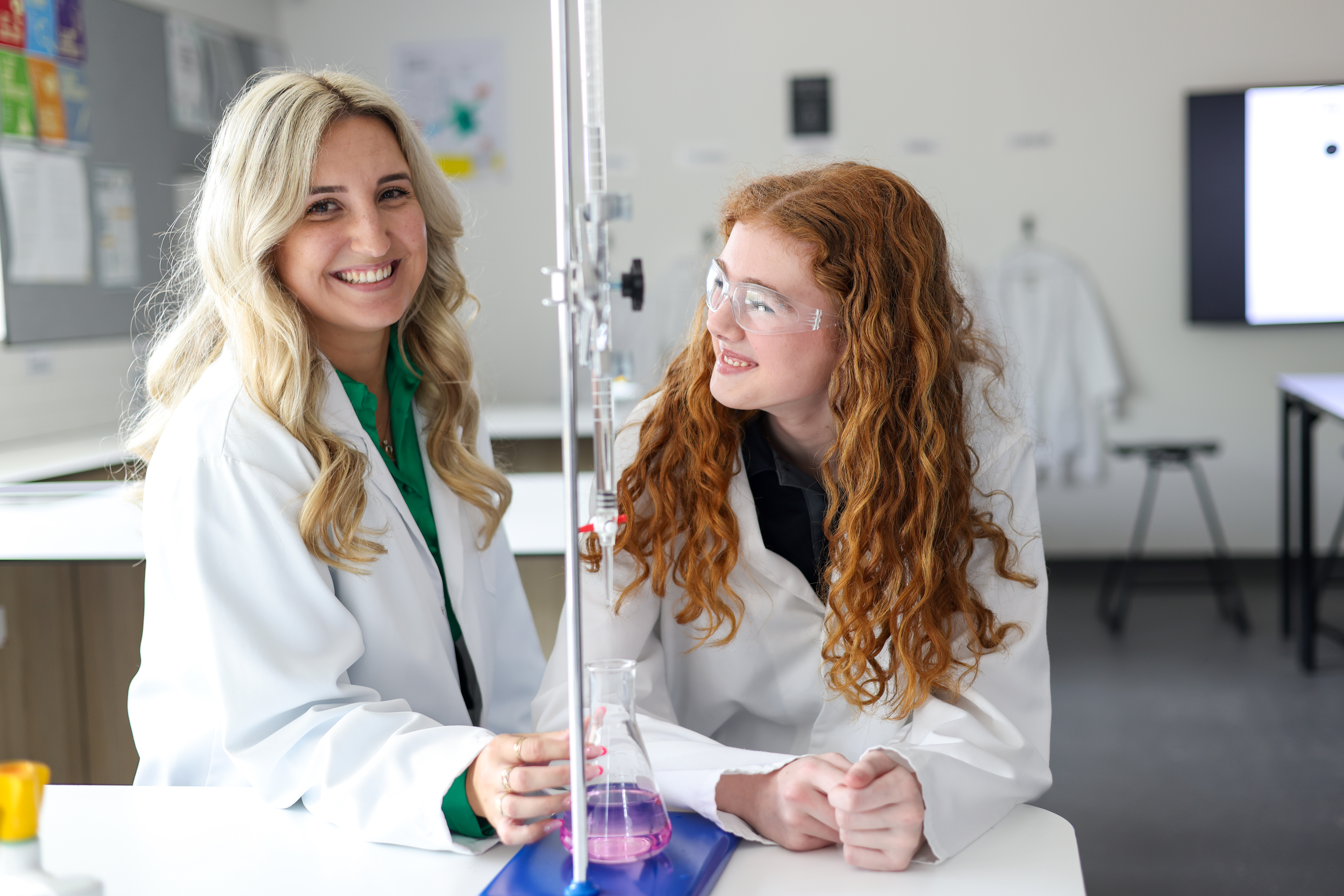 Teacher and student in lab coats running a chemistry experiment