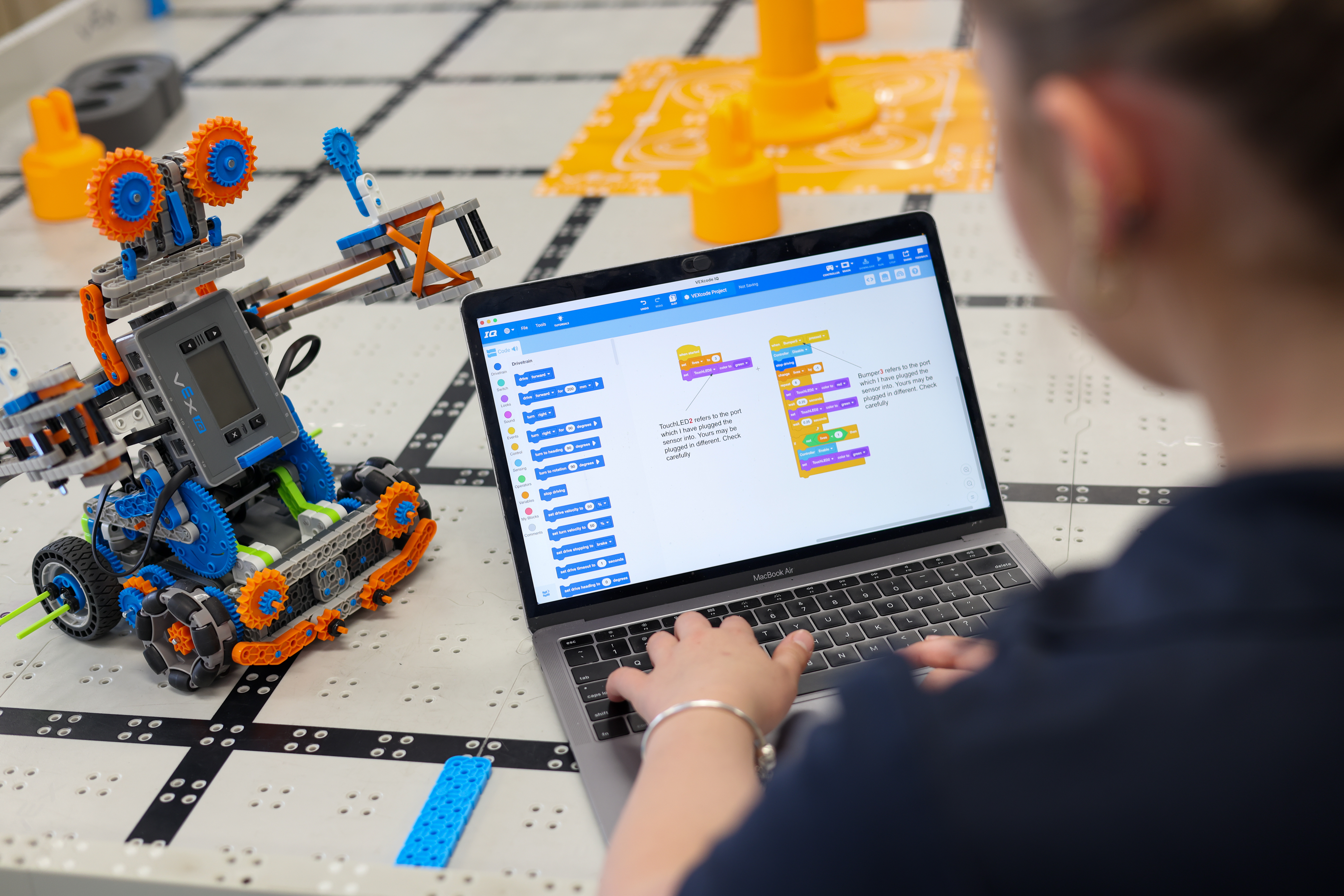 Student programming a LEGO robotics model on a laptop