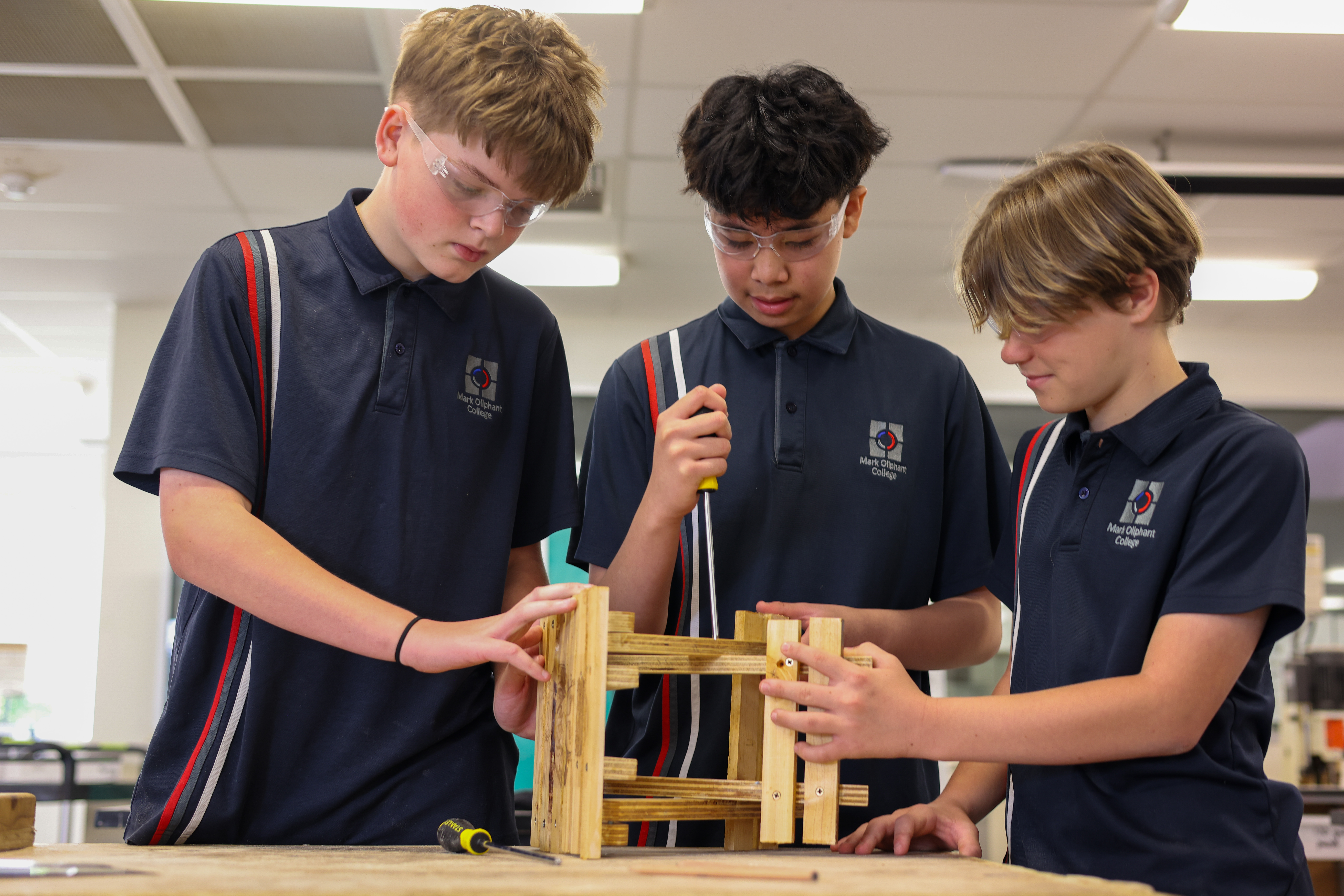 Three secondary students building a timber frame in a design and technology class