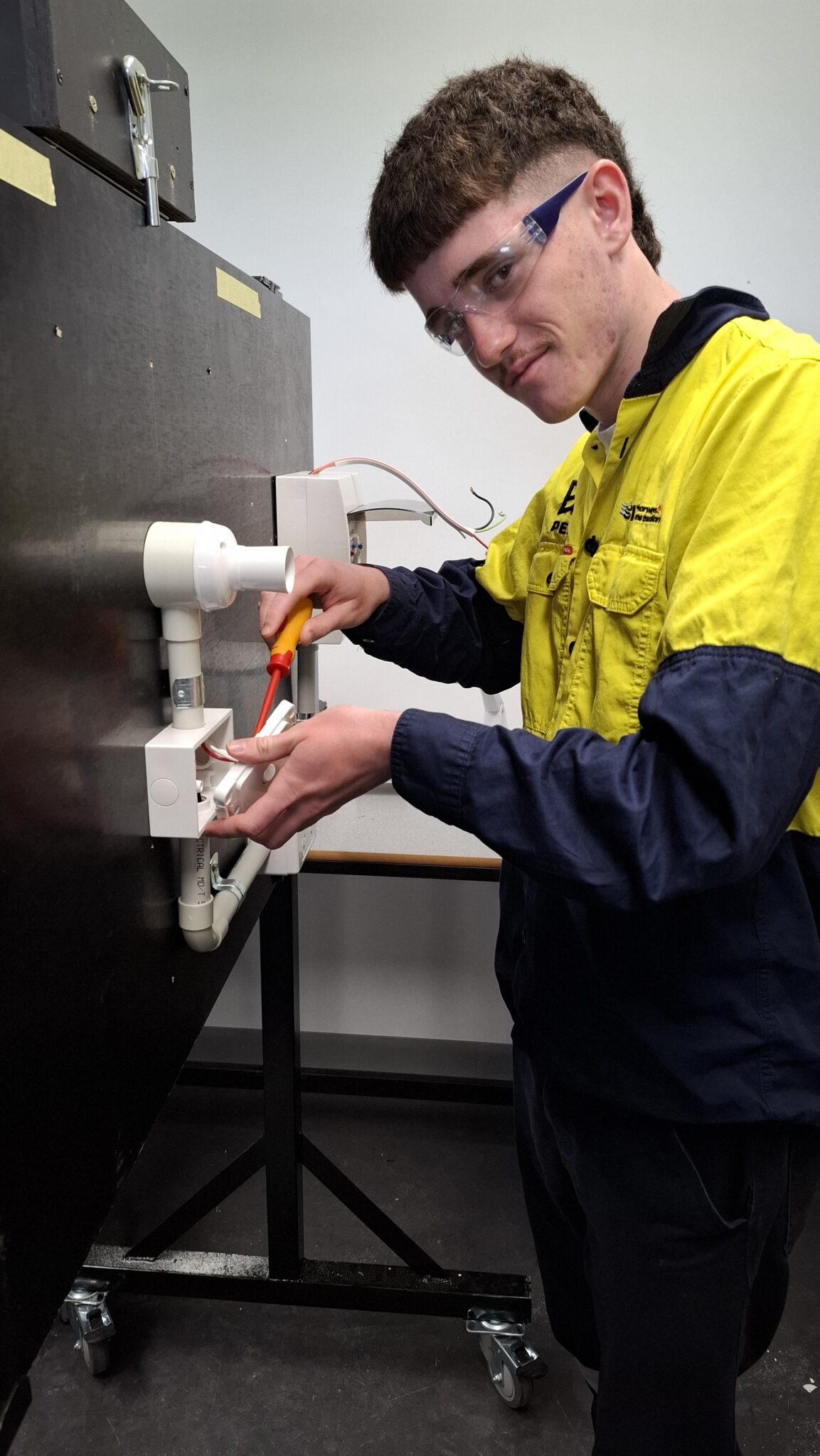 VET student practising plumbing work in a training bay