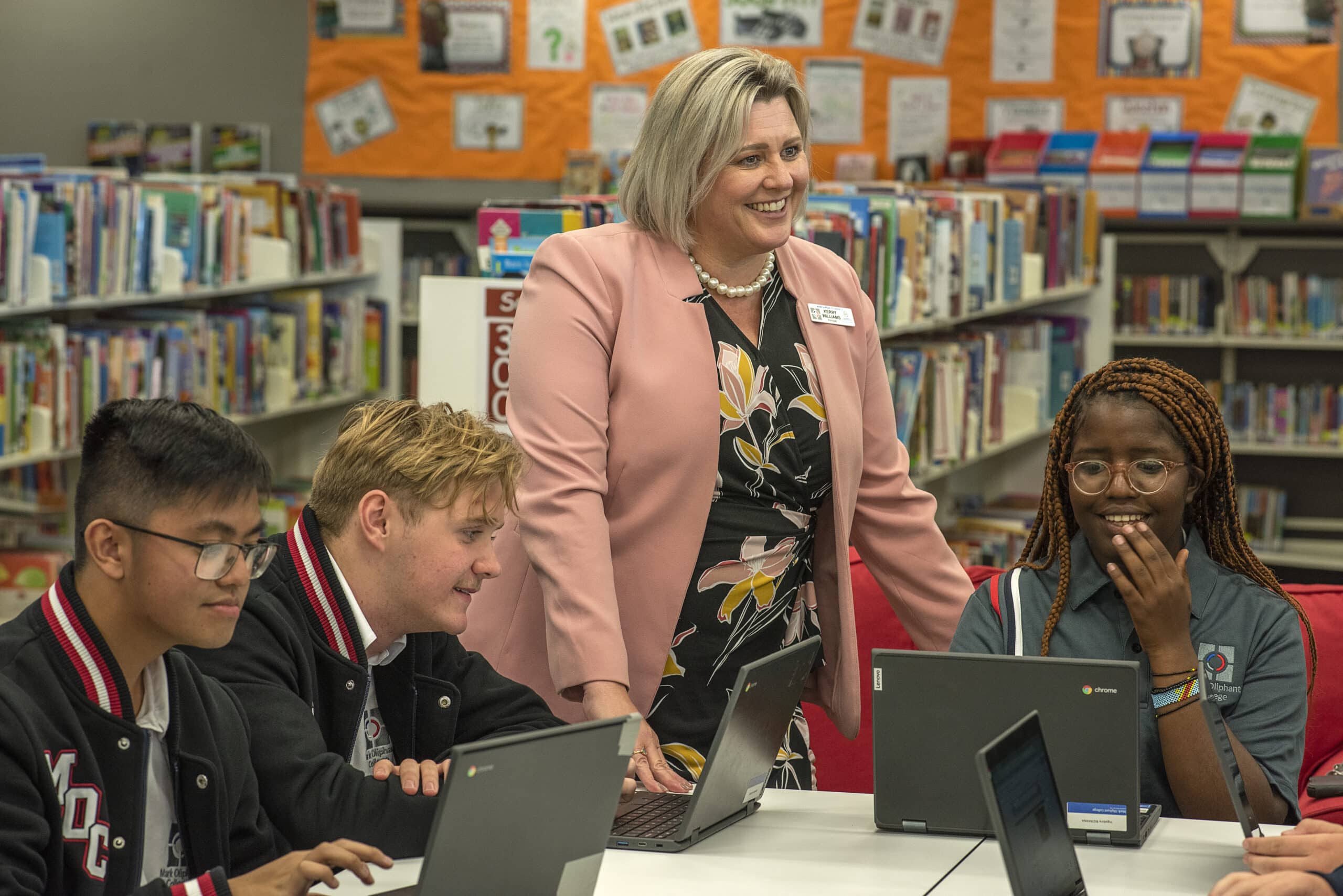 Teacher supporting students working on laptops in the library