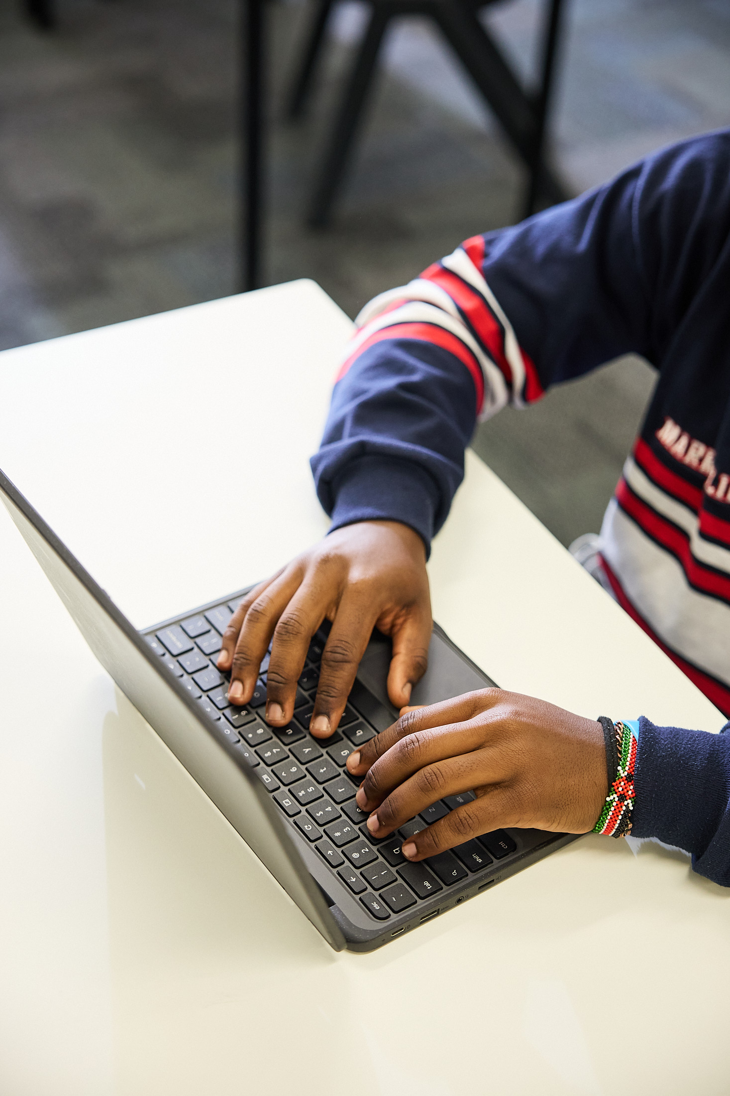 Close-up of a student typing on a laptop keyboard