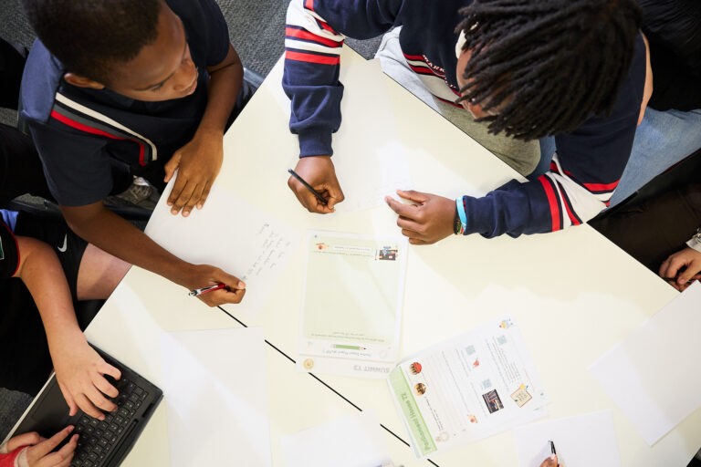 Students working on written activities at a table, viewed from above