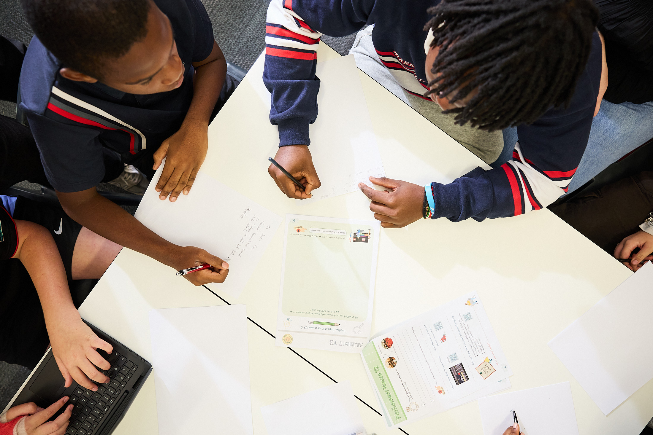 Students working on written activities at a table, viewed from above
