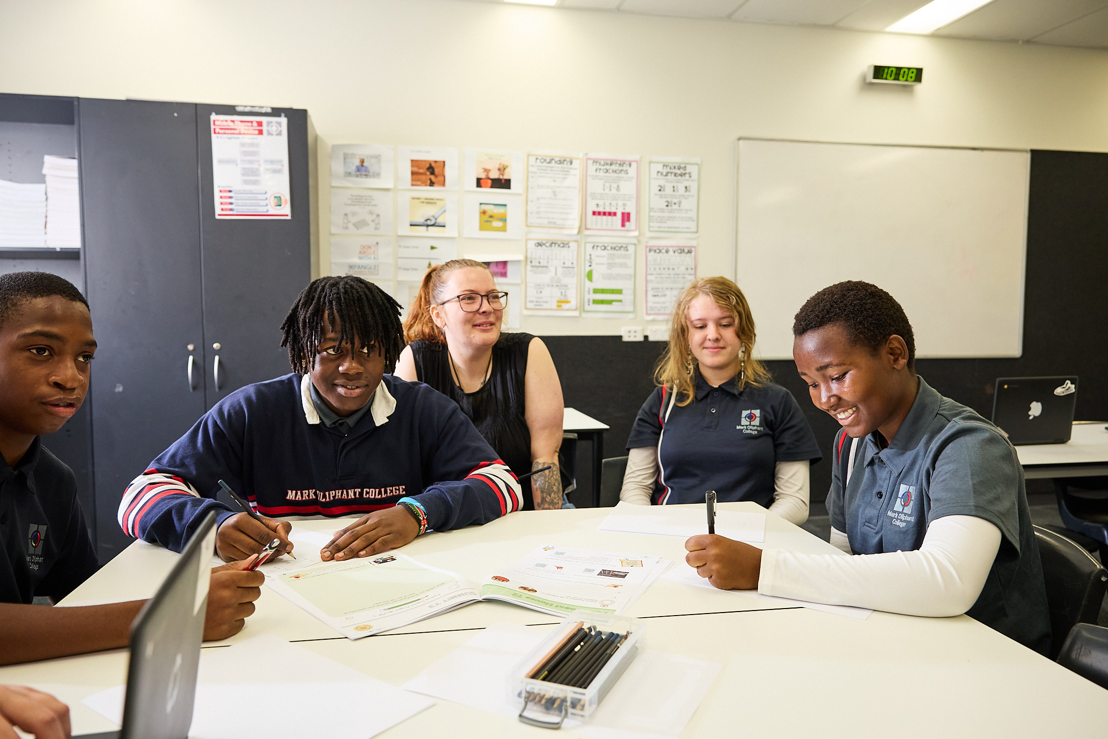 Secondary students working together at a table with their teacher