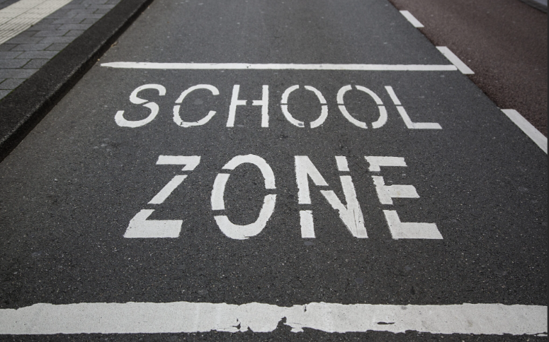 School zone road marking painted on the street outside the school
