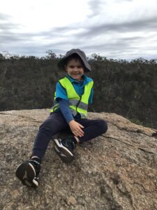 Bush Kindy child sitting on a large rock during an outdoor session