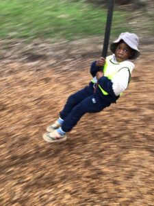 Bush Kindy child swinging on a rope swing in the bush