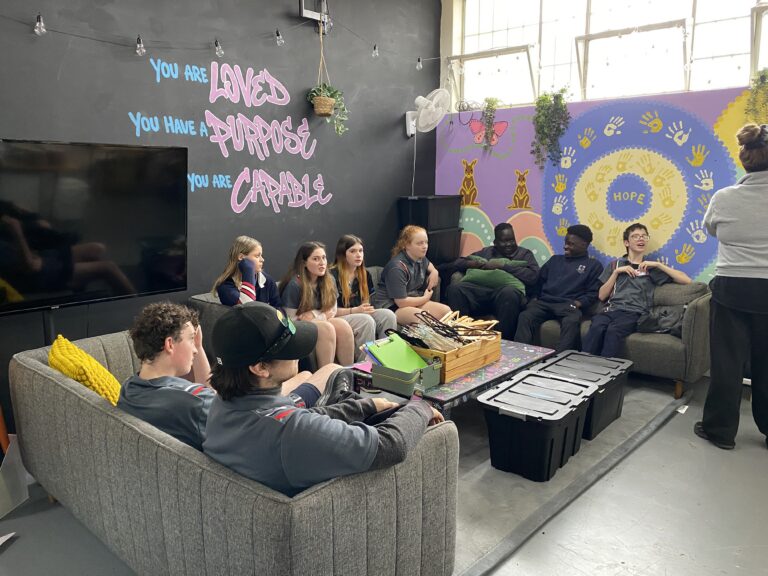 Students relaxing on couches in the wellbeing space, with murals reading 'You are loved, you have a purpose, you are capable'