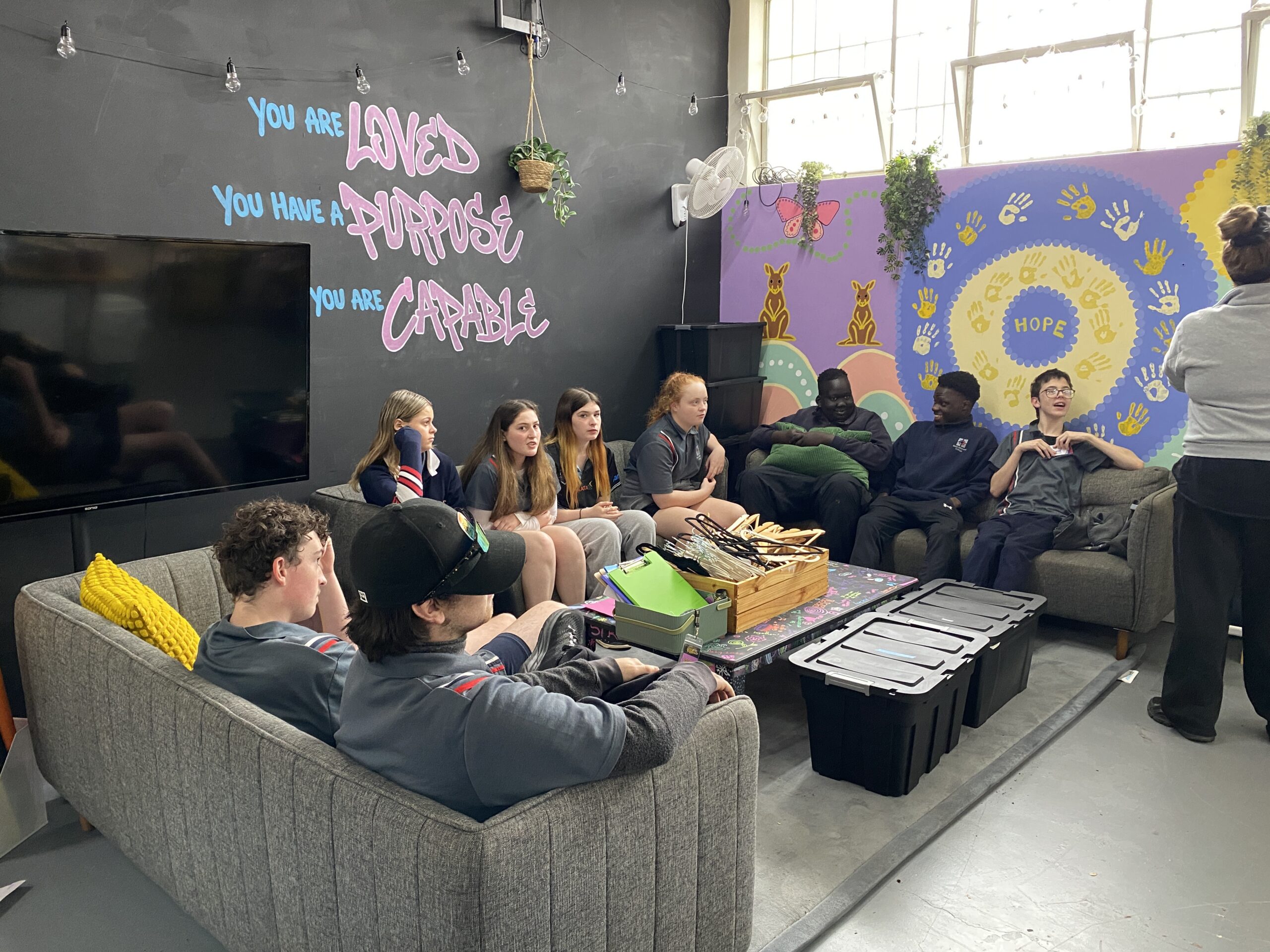 Students relaxing on couches in the wellbeing space, with murals reading 'You are loved, you have a purpose, you are capable'