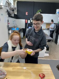 Two students icing a cupcake in the food technology kitchen