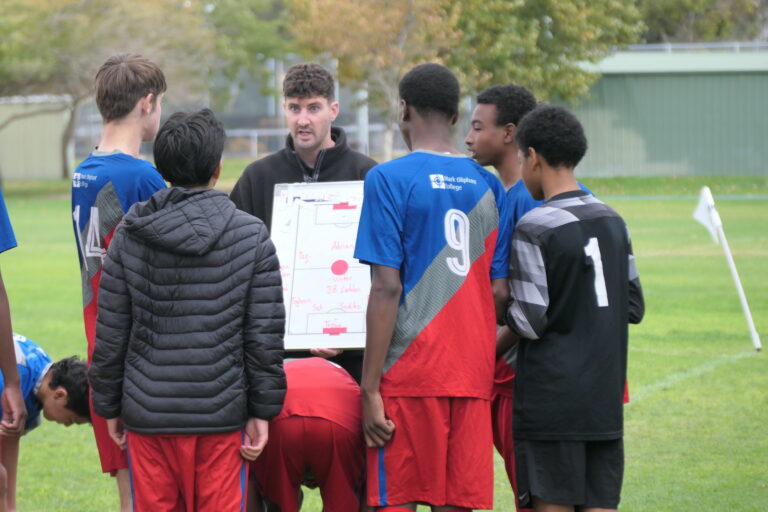 Coach briefing the Year 9/10 boys knockout soccer team using a tactics board