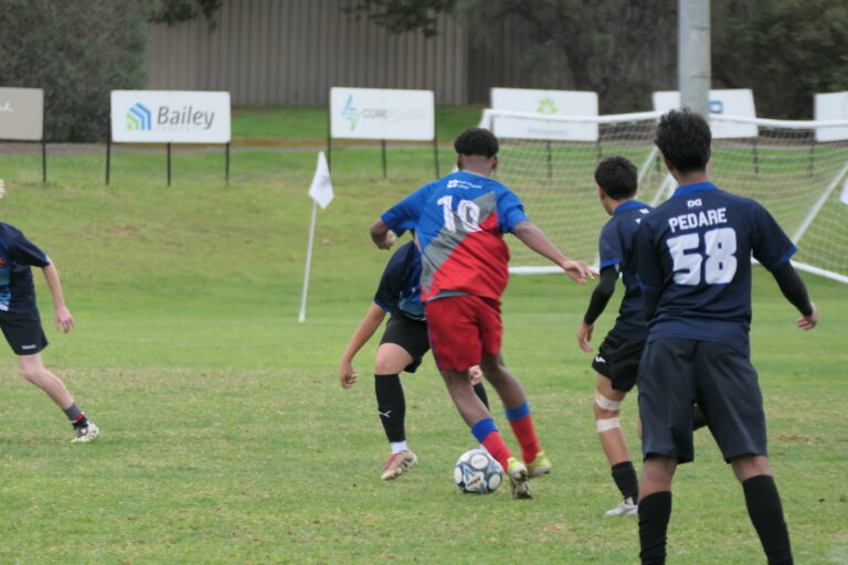 Mark Oliphant College player taking the ball past a Pedare opponent