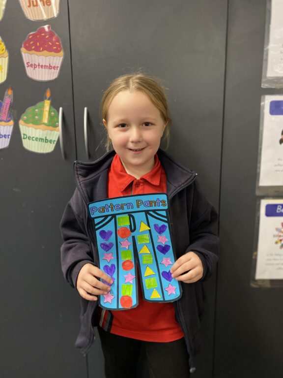 Year 1D student holding their blue and yellow Pattern Pants artwork