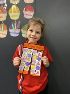 Year 1D student holding their orange Pattern Pants artwork decorated with shapes
