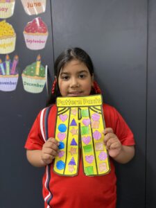 Year 1D student holding their yellow Pattern Pants artwork decorated with shapes