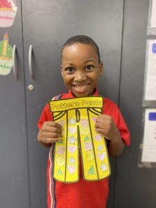 Year 1D student holding their yellow Pattern Pants artwork decorated with hearts